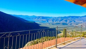 A balcony with a metal railing overlooking a mountainous landscape.