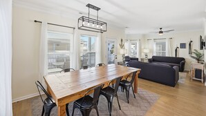 A spacious living room with a wooden dining table, black chairs, a dark sofa, and a ceiling fan. - Country music festival! Ocean Lake Campground house.  (Myrtle Beach)