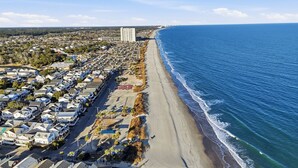 An aerial view of a coastal residential area with a beachfront, houses, and a large building in the distance. - Country music festival! Ocean Lake Campground house.  (Myrtle Beach)