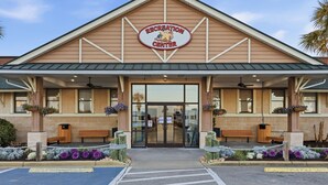A recreation center with a large entrance, two wooden benches, and flower planters. - Country music festival! Ocean Lake Campground house.  (Myrtle Beach)