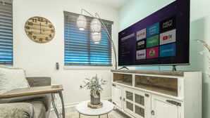 A living room with a TV displaying streaming services, a wooden clock, and a window with blinds. - ✤VILLA CATALINA✤ Private Studio #103 (Chattanooga)