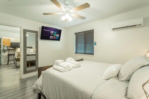 A hotel room with a bed, a ceiling fan, an air conditioning unit, a TV mounted on the wall, and a window with blinds. - ✤VILLA CATALINA✤ Private Studio #103 (Chattanooga)