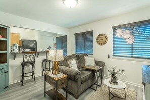A living room with a grey sofa, a coffee table, a lamp, a small side table, and a potted plant. - ✤VILLA CATALINA✤ Private Studio #103 (Chattanooga)