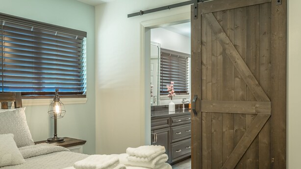 A bedroom with a bed, a nightstand with a lamp, a wooden door, and a bathroom visible through an open door. - ✤VILLA CATALINA✤ Private Studio #103 (Chattanooga)