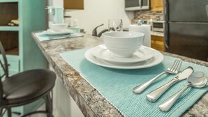 A kitchen counter with a white bowl, plate, and cutlery set on a teal placemat. - ✤VILLA CATALINA✤ Private Studio #103 (Chattanooga)