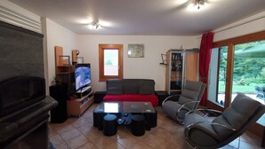 Un salon avec une cheminée, un téléviseur, un canapé, une table basse et un fauteuil.