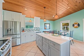 Una cocina moderna con electrodomésticos de acero inoxidable, una isla grande y un techo de madera.