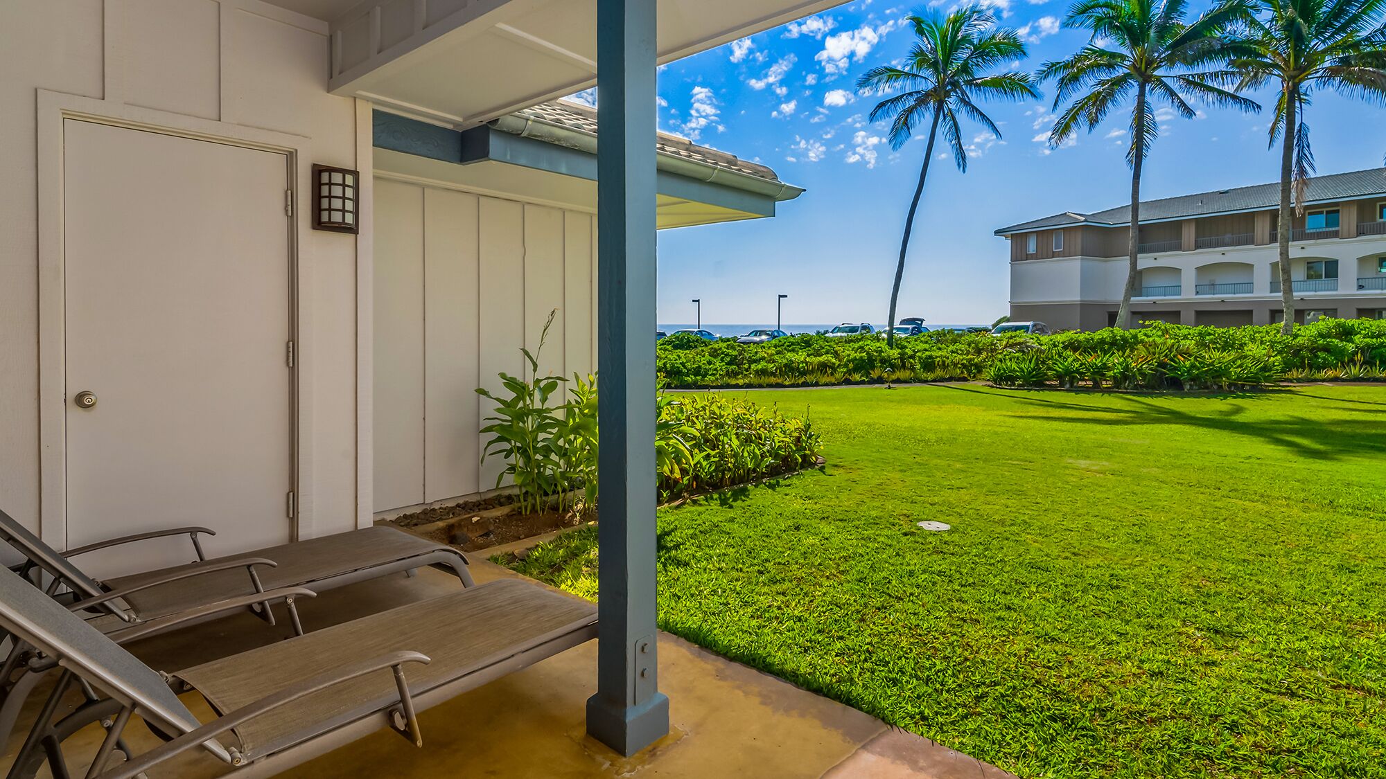 A hotel entrance with a covered porch, a pool, and a view of a building with a balcony.