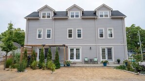 A two-story house with a covered porch, a small garden, and a front door. - The Grey Beach House!! In the heart of Grand Bend (Grand Bend)