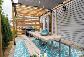 Enjoy dining and socializing in this outdoor patio area with a grill and comfortable seating.