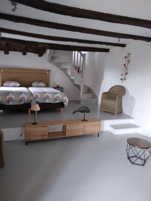 A bedroom with a wooden bed, a chair, a lamp, and a staircase.