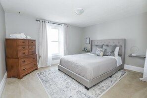 Une chambre à coucher avec un lit, une commode et une fenêtre avec des rideaux.