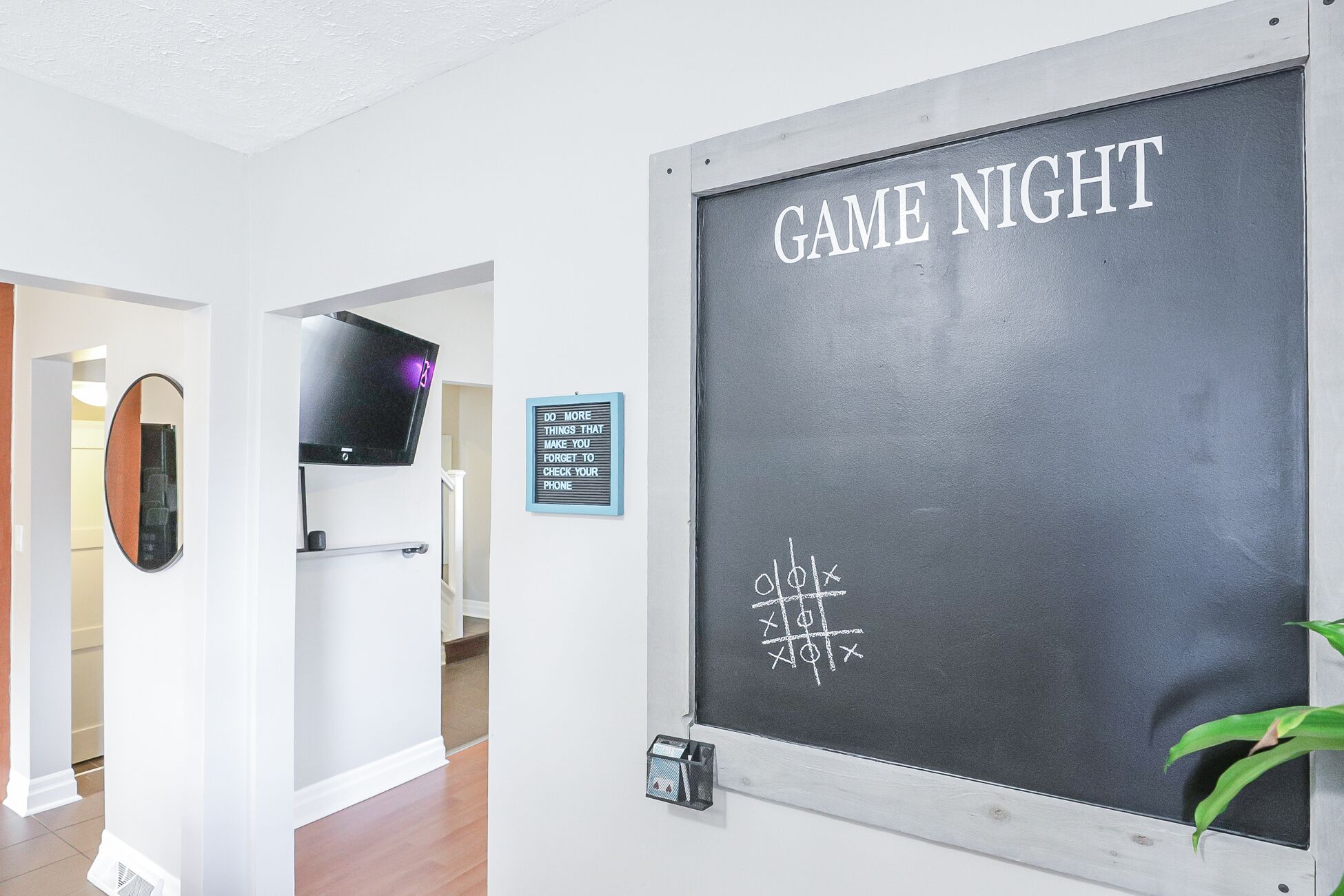 Um quarto com um quadro negro exibindo 'GAME NIGHT' e uma placa com texto motivacional.