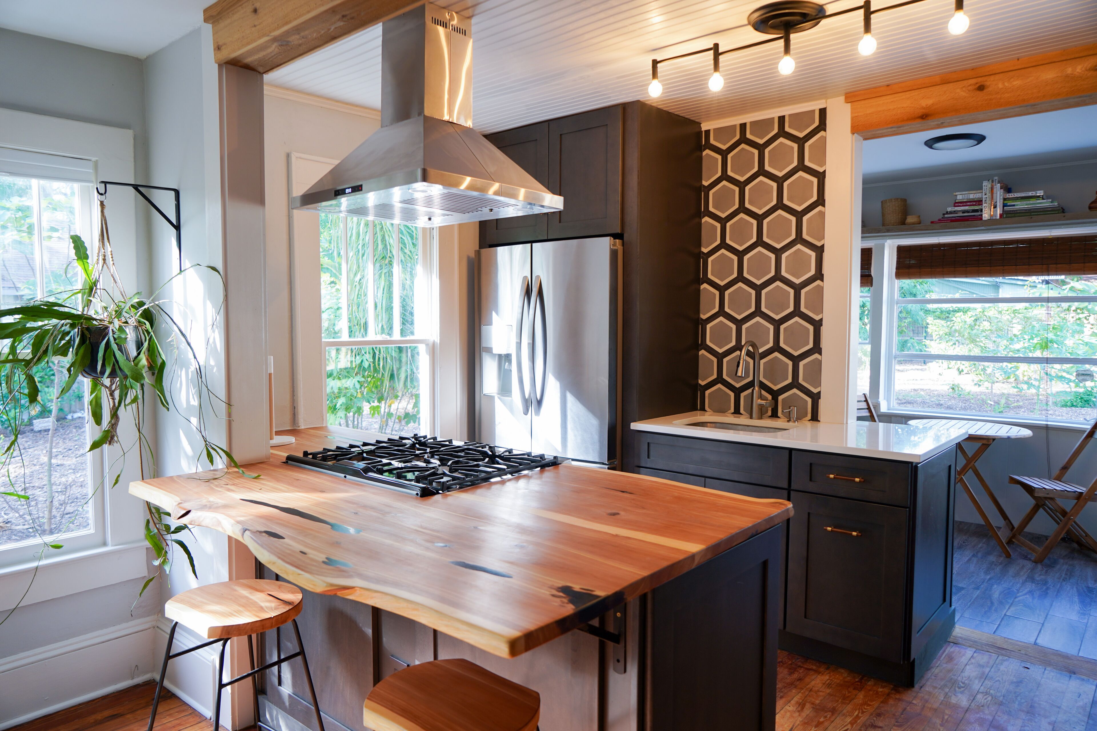A modern kitchen with a central island, dark cabinetry, and a hexagonal patterned backsplash.