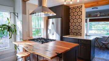 A modern kitchen with a central island, dark cabinetry, and a hexagonal patterned backsplash.