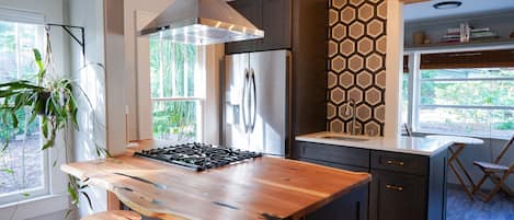 A modern kitchen with a central island, dark cabinetry, and a hexagonal patterned backsplash.
