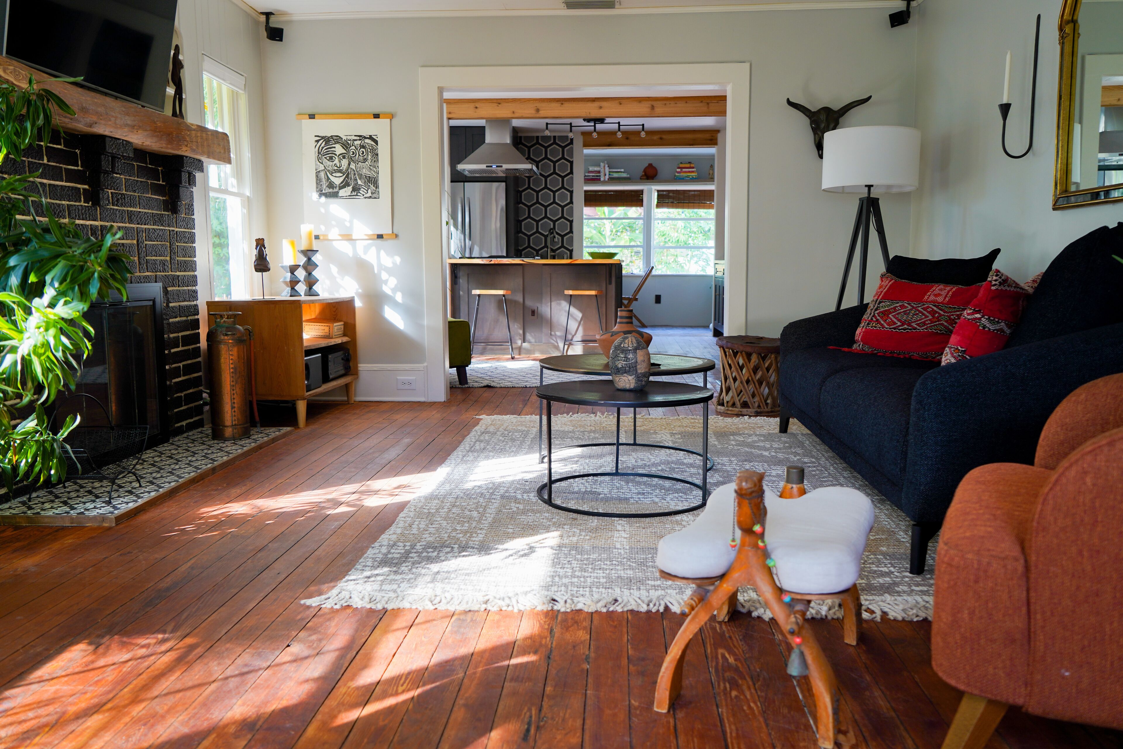 A cozy living room with a fireplace, a dining area, and a kitchen visible through an open doorway.