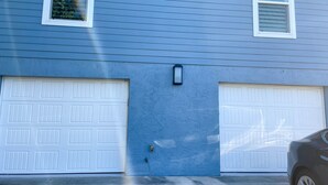 Una casa azul con dos puertas de garaje blancas y una pequeña cámara de seguridad negra en la pared.
