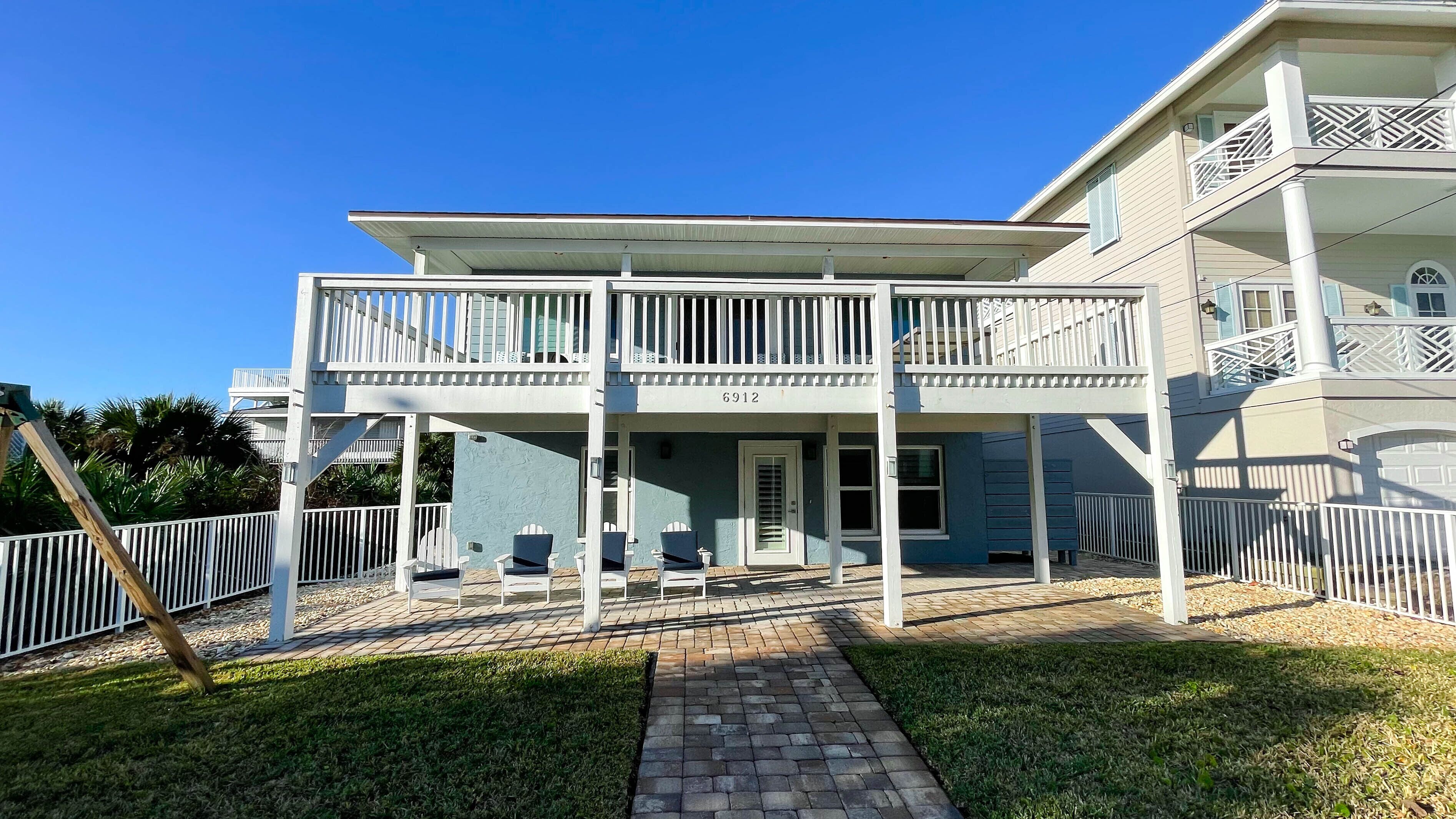 A two-story house with a balcony, a covered porch, and a paved walkway.