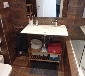 Een bad/douchecombinatie, een haardroger, handdoeken