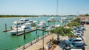 A marina with boats docked, a parking area with cars, and a clear view of the water and distant buildings. - BB's - Perfect Choice For Your Beaufort Vacation! (Beaufort)