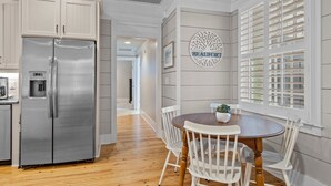 A kitchen with a stainless steel refrigerator, a dining table with white chairs, and a wall-mounted sign that reads "BEAUFORT". - BB's - Perfect Choice For Your Beaufort Vacation! (Beaufort)