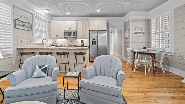 A modern kitchen with white cabinets, stainless steel appliances, and a dining area with white chairs and a table. - BB's - Perfect Choice For Your Beaufort Vacation! (Beaufort)