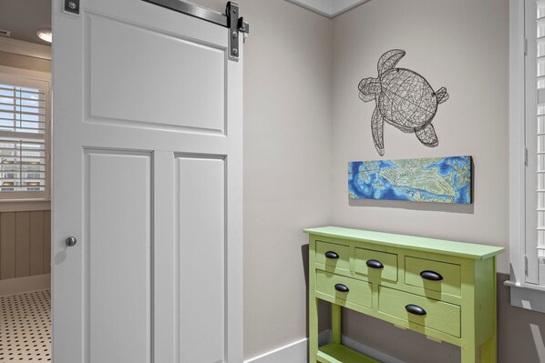 A room with a white door, a green dresser, a wall map, and a wall art of a turtle.
