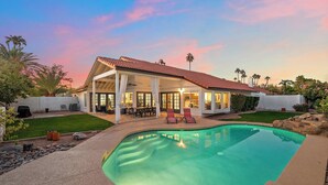 Une maison avec une piscine, un patio couvert et une pelouse bien entretenue.