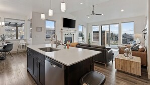 A spacious kitchen with a central island, a dining area, and a living room with a fireplace.
