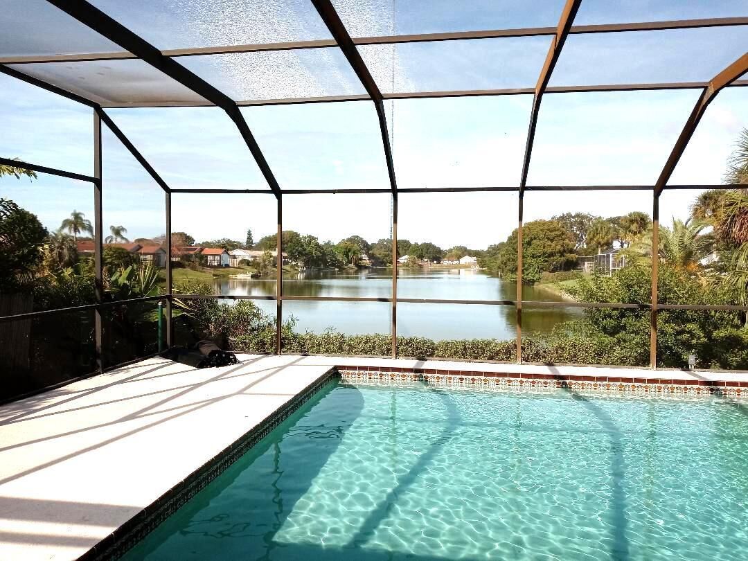 Una piscina con vistas despejadas a un lago y follaje circundante.