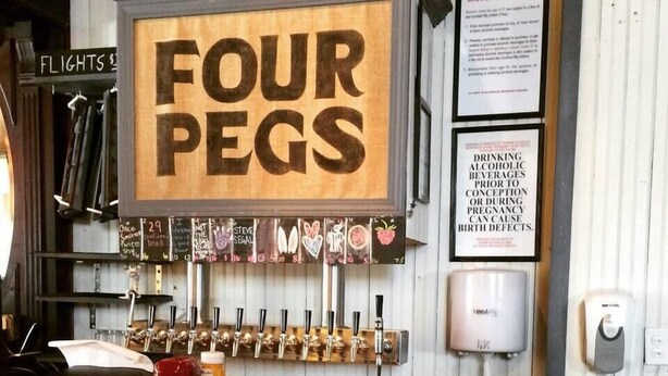Zona de bar con un letrero que dice "FOUR PEGS" y varios grifos de cerveza.