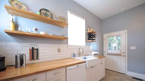 Una cocina con armarios blancos, encimera de madera, un lavabo y una ventana.