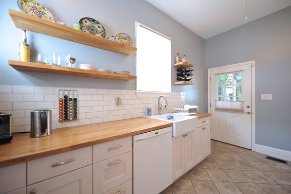 Una cocina con armarios blancos, encimera de madera, un lavabo y una ventana.