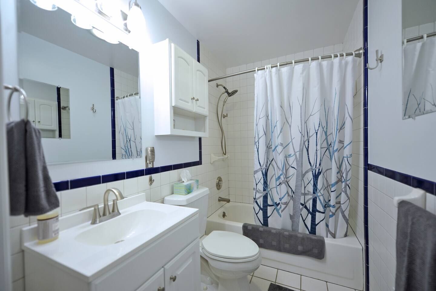 A bathroom with a white sink, vanity, toilet, and shower area.