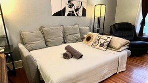 Una cama bien hecha con una toalla enrollada, un cojín con forma de bicicleta y un cojín con estampado de girasol.