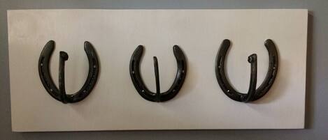 Three black horseshoes mounted on a white rectangular panel.