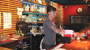Un bar con un letrero de madera que dice "SAVILLE POST" y una variedad de botellas de licores en estantes.
