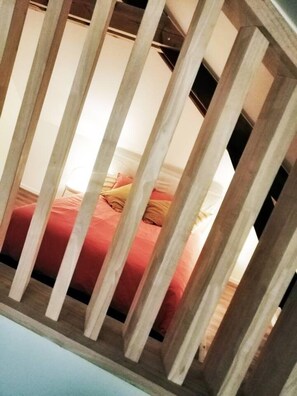 Ein Zimmer mit einem Bett, einem Holz-Kopfteil und einem Fenster.