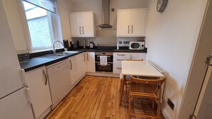 A compact kitchen with white cabinets, a microwave, a sink, and a wooden floor.