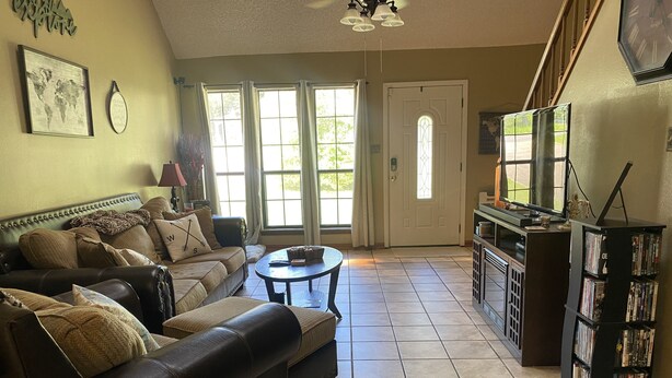 A living room with a leather sofa, a coffee table, and a bookshelf filled with DVDs. - Sylvan Lakes Quiet Place (West Monroe)