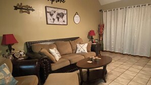 A living room with a sofa, two armchairs, a coffee table, and a world map on the wall. - Sylvan Lakes Quiet Place (West Monroe)