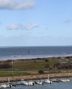 A marina with boats docked, a statue in the distance, and a clear sky. - Charming apartment (Courseulles-sur-Mer)