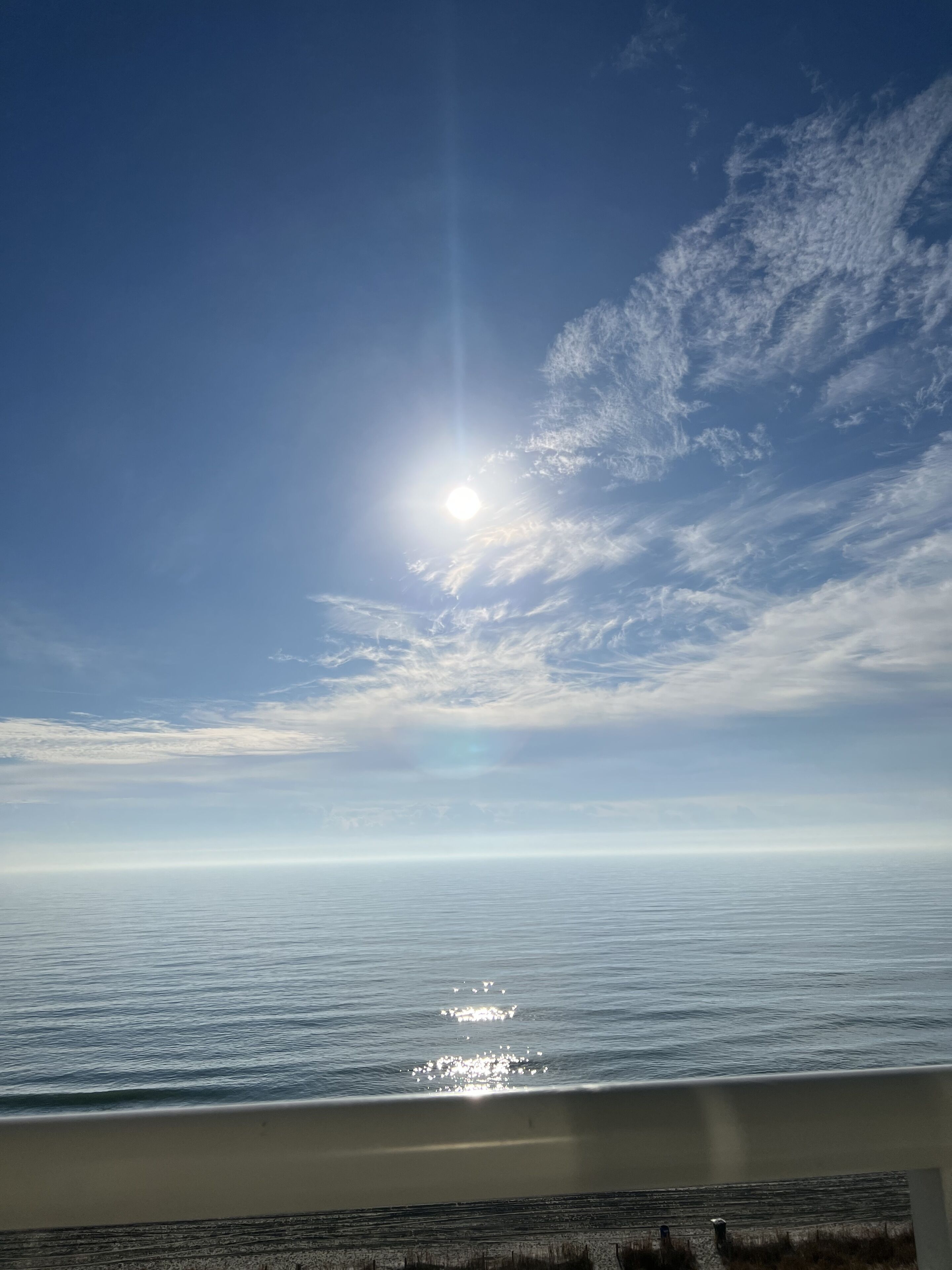 A view of the ocean with the sun shining through the clouds.