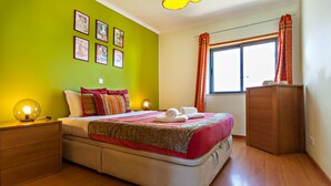 A bedroom with a bed, bedside tables, a wardrobe, and a window with curtains. - Magnificent view (Faro)