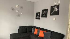 Una sala de estar moderna con un sofá modular, detalles decorativos en la pared y piso de madera.