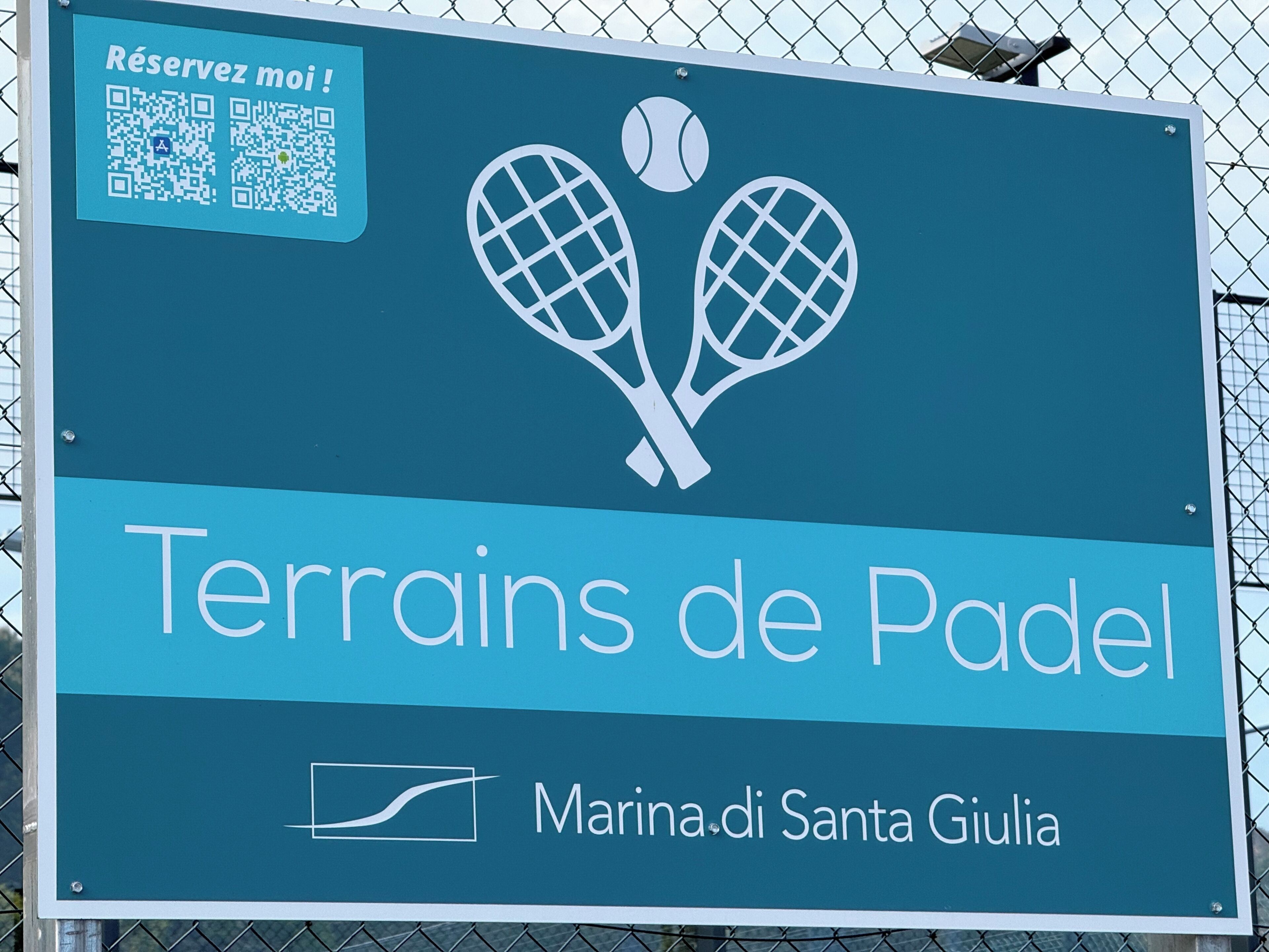A sign for 'Terrains de Padel' with a QR code and a tennis racket graphic.
