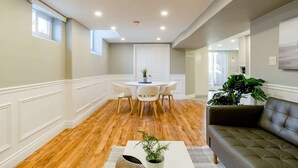 Un salon moderne comprenant un coin repas, un plancher en bois, un canapé gris et une plante en pot.