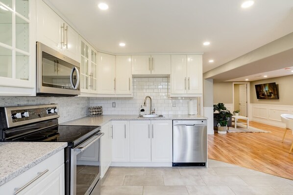A modern kitchen with white cabinets, stainless steel appliances, and a tiled backsplash. - Grimsby Lakeview Suite l 2 Min Walk to Lake Ontario l King Bed l Great Value (Grimsby)