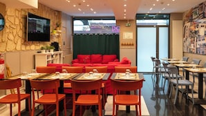 A restaurant with red seating, a TV mounted on the wall, and a menu board.